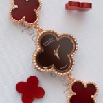 Van Cleef & Arpels watch with a brown dial and red mother-of-pearl clover motif.