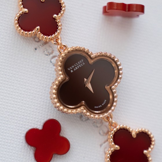 Van Cleef & Arpels watch with a brown dial and red mother-of-pearl clover motif.