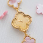 Van Cleef & Arpels watch with a gold dial featuring a pink mother-of-pearl clover motif.