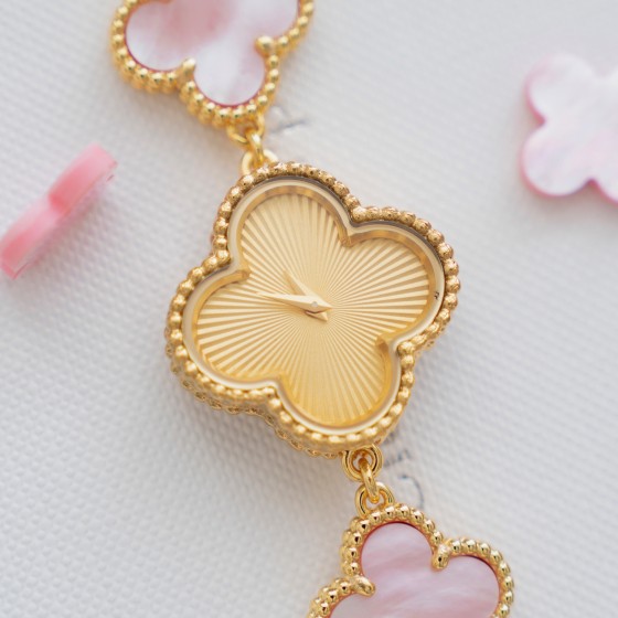 Van Cleef & Arpels watch with a gold dial featuring a pink mother-of-pearl clover motif.