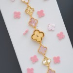Van Cleef & Arpels watch with a gold dial featuring a pink mother-of-pearl clover motif.