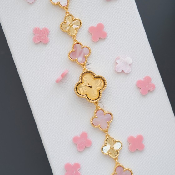 Van Cleef & Arpels watch with a gold dial featuring a pink mother-of-pearl clover motif.