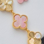 Van Cleef & Arpels watch with a gold dial featuring a pink mother-of-pearl clover motif.