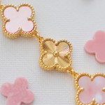 Van Cleef & Arpels watch with a gold dial featuring a pink mother-of-pearl clover motif.